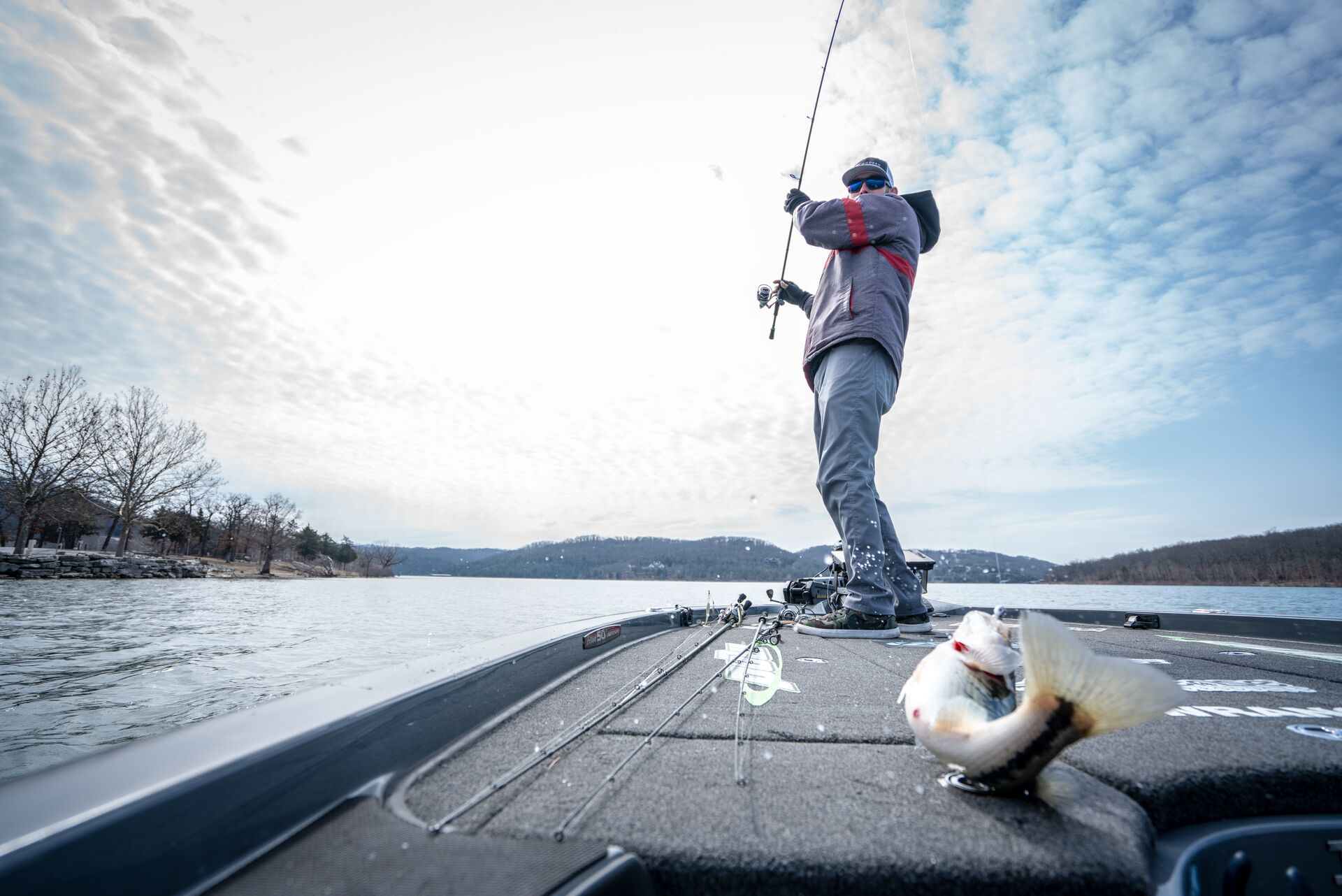 A man stands on a boat and reels in a fish, boating license for fishing boats concept. 