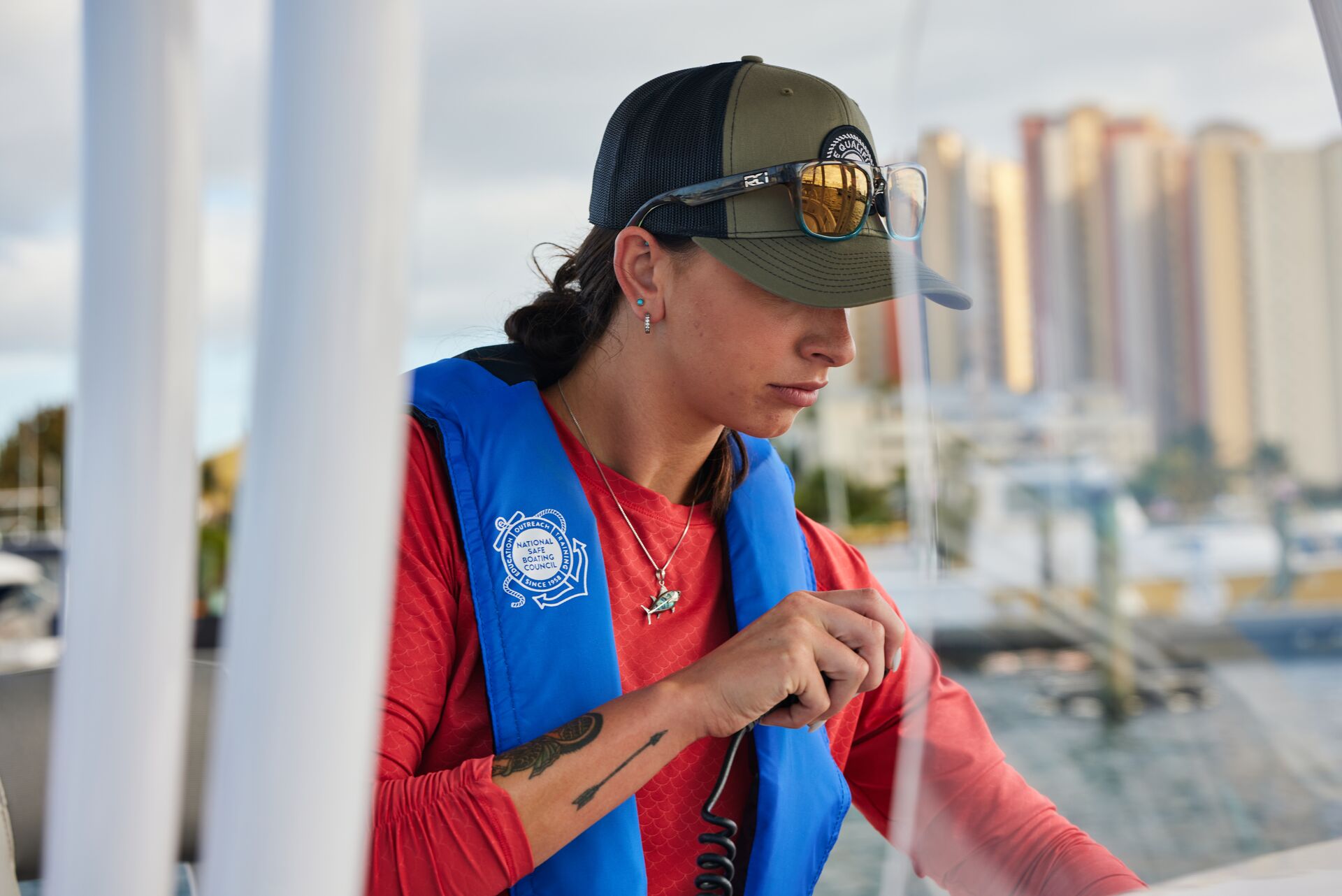 A woman wearing a lifejacket on a boat using a radio, yacht safety equipment concept. 